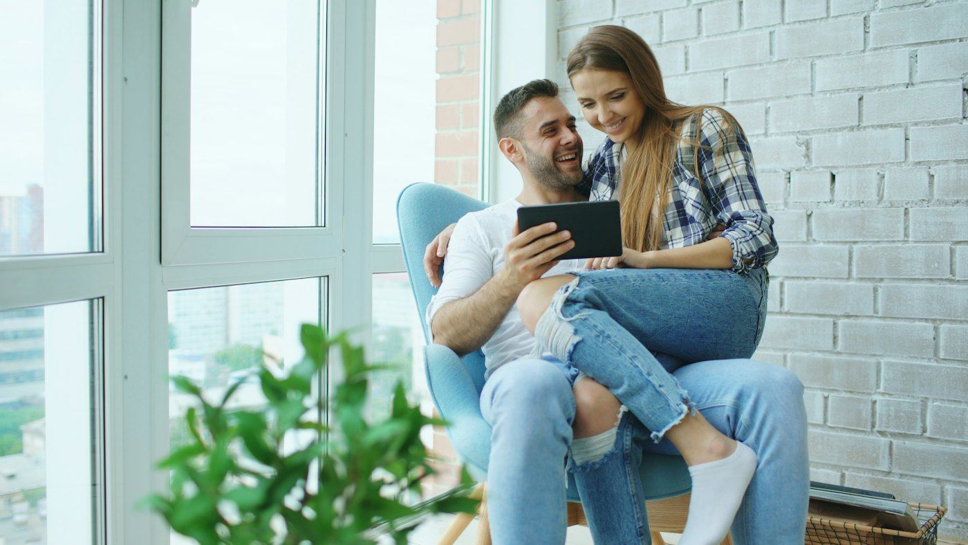 Couple sitting together, looking at a tablet